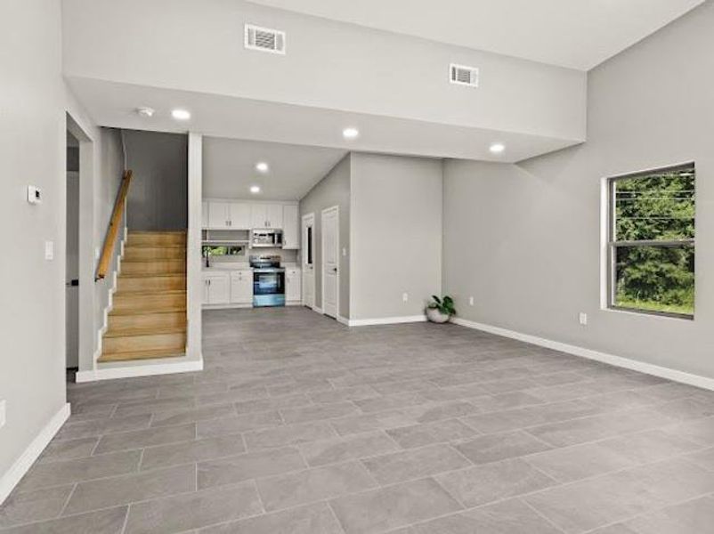 Unfurnished living room featuring stairway and recessed lighting