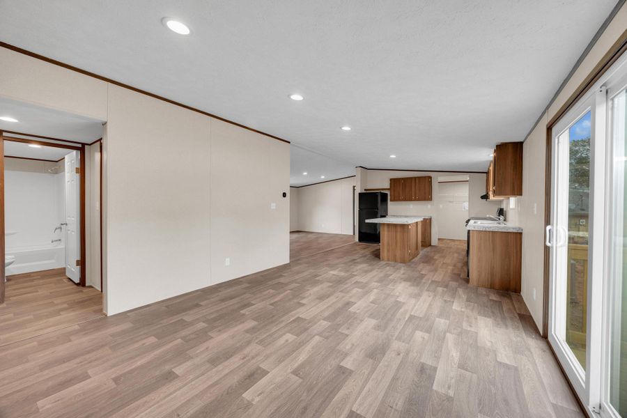 Kitchen with brown cabinetry, light wood-style flooring, light countertops, open floor plan, and freestanding refrigerator