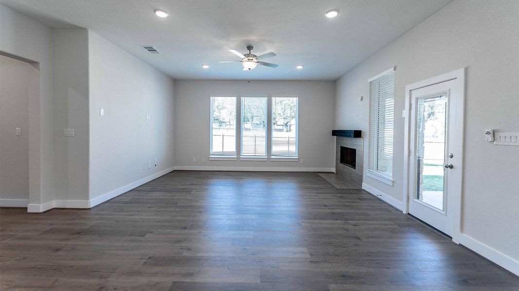 Unfurnished living room with plenty of natural light, a glass covered fireplace, ceiling fan, recessed lighting, and dark wood finished floors Unfurnished living room with plenty of natural light, a glass covered fireplace, ceiling fan, recessed lighting, and dark wood finished floors
