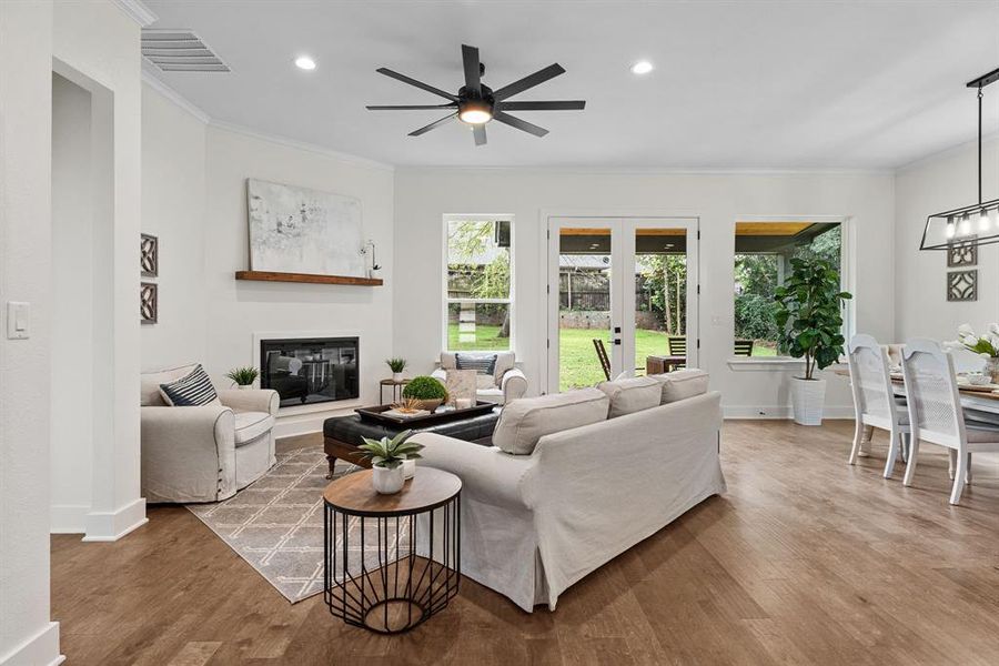 Living room featuring ornamental molding, ceiling fan with notable chandelier, and hardwood / wood-style floors Living room featuring ornamental molding, ceiling fan with notable chandelier, and hardwood / wood-style floors