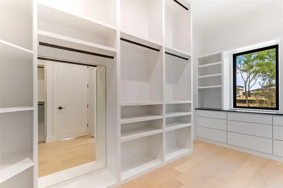 Spacious closet with light wood-type flooring Spacious closet with light wood-type flooring