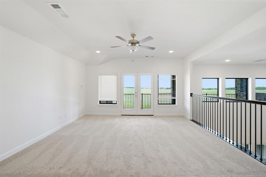 Spacious upper-level room featuring light-colored carpeting, white walls, and a ceiling fan Spacious upper-level room featuring light-colored carpeting, white walls, and a ceiling fan