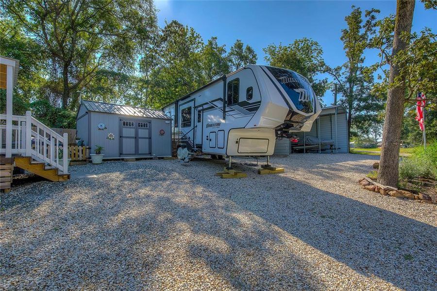 View of side of property showing storage shed, RV parking space, four-space carport.