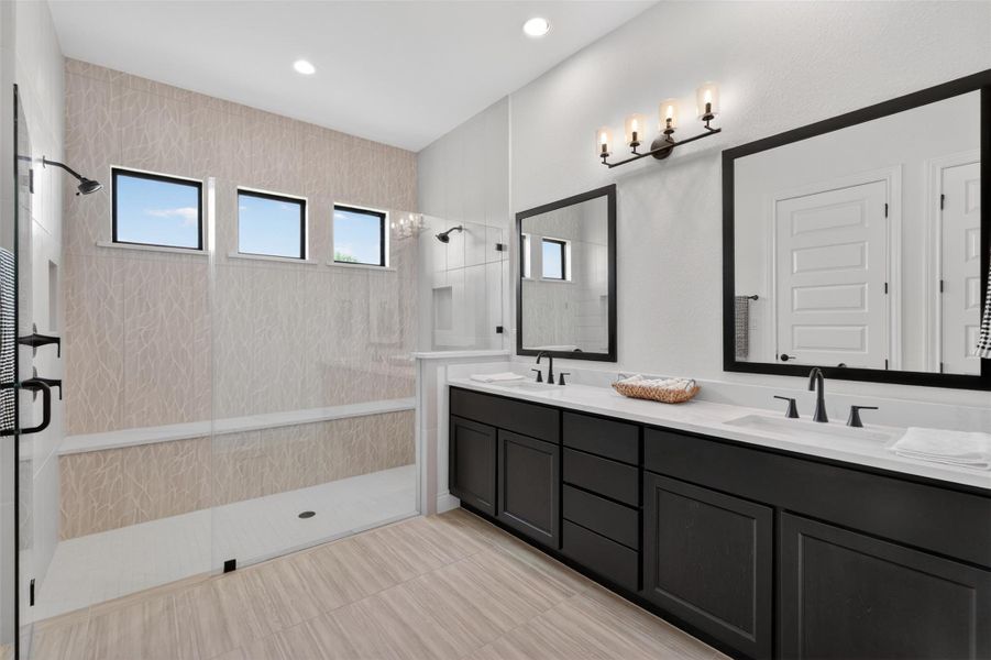 Modern primary bathroom featuring dual vanities, walk-in shower, and natural light. Modern primary bathroom featuring dual vanities, walk-in shower, and natural light.