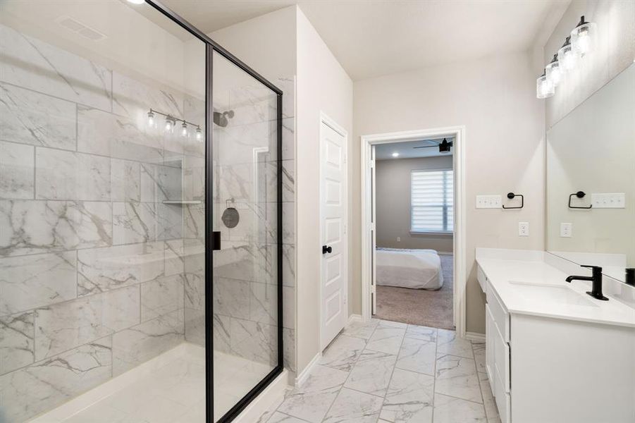 Full bathroom featuring vanity, a marble finish shower, light marble finish floors, ensuite bathroom, and a ceiling fan Full bathroom featuring vanity, a marble finish shower, light marble finish floors, ensuite bathroom, and a ceiling fan