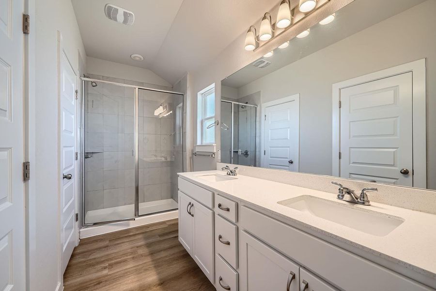 Full bath featuring double vanity, wood finished floors, a sink, and visible vents