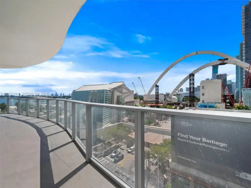 Expansive curved balcony featuring tile flooring and a glass railing Expansive curved balcony featuring tile flooring and a glass railing