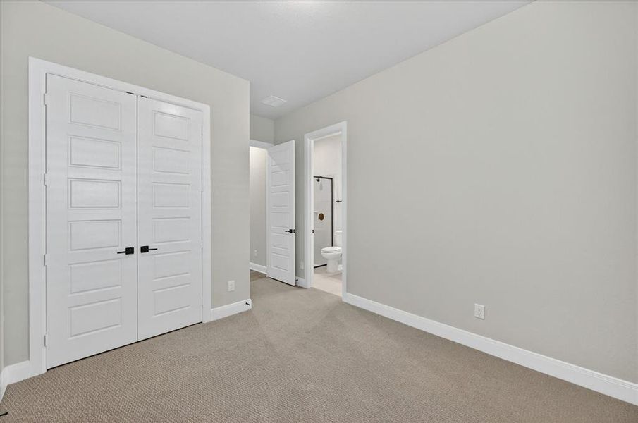 Neutral toned room with plush carpeting, featuring white paneled double doors with matte black hardware Neutral toned room with plush carpeting, featuring white paneled double doors with matte black hardware