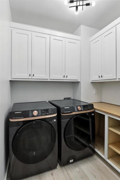 Laundry area with cabinet space, washer and dryer, and light wood finished floors