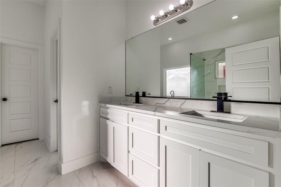 Full bathroom with light marble finish flooring, double vanity, and a marble finish shower