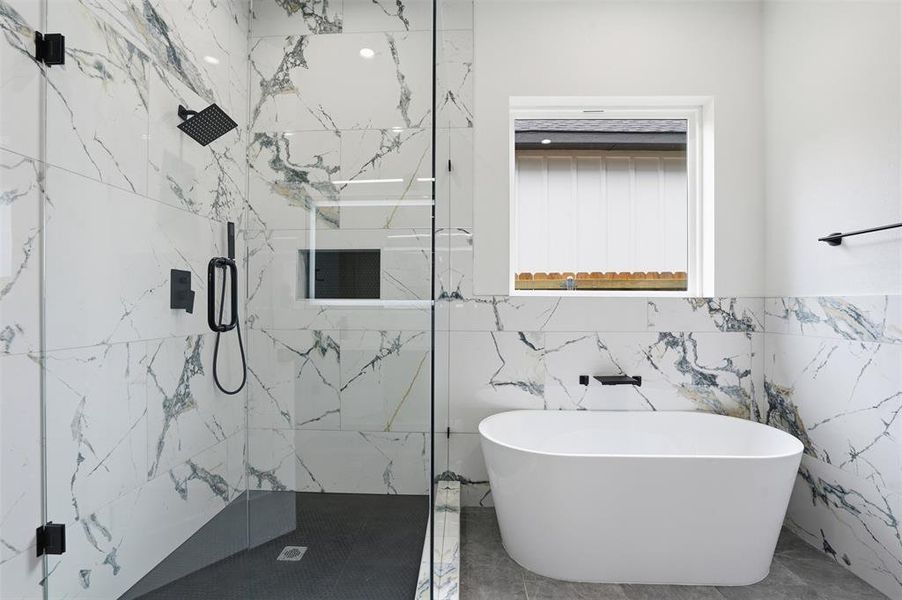 Contemporary bathroom featuring a freestanding soaking tub, a frameless glass shower enclosure with matte black fixtures, and floor-to-ceiling marbled tile