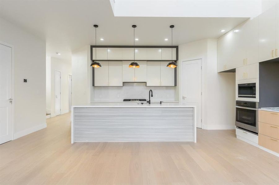 Kitchen with pendant lighting, stainless steel appliances, light wood-style floors, white cabinets, and recessed lighting Kitchen with pendant lighting, stainless steel appliances, light wood-style floors, white cabinets, and recessed lighting