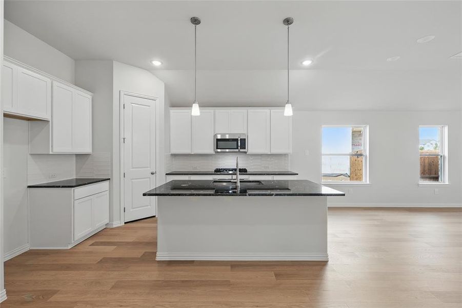 Kitchen featuring a kitchen island with sink, white cabinetry, and light wood-style flooring