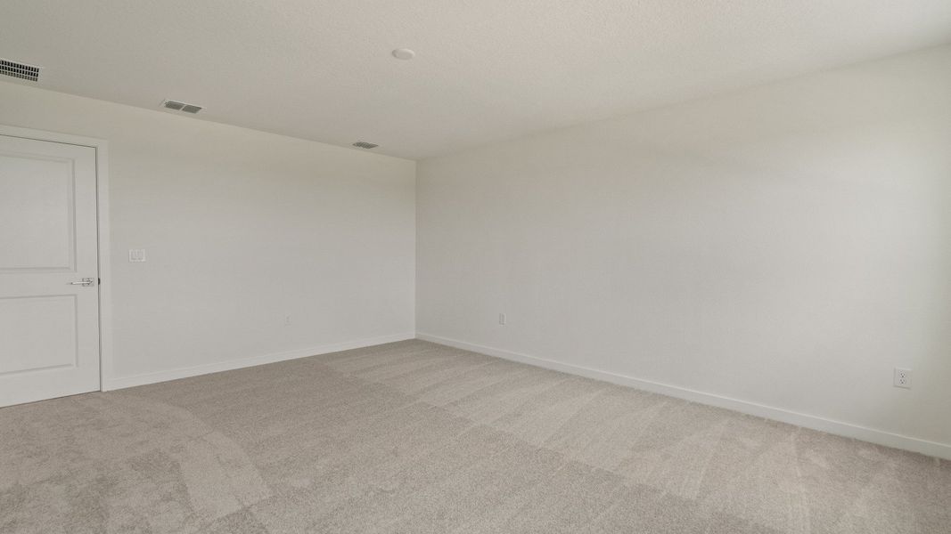 Expansive primary suite offers comfort and privacy with soft carpet, generous layout, and attached ensuite bath