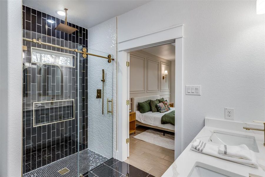 Bathroom featuring hardwood / wood-style flooring, vanity, and a tile shower