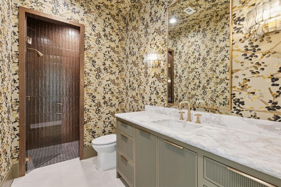 Bathroom featuring a shower stall, wallpapered walls, and vanity