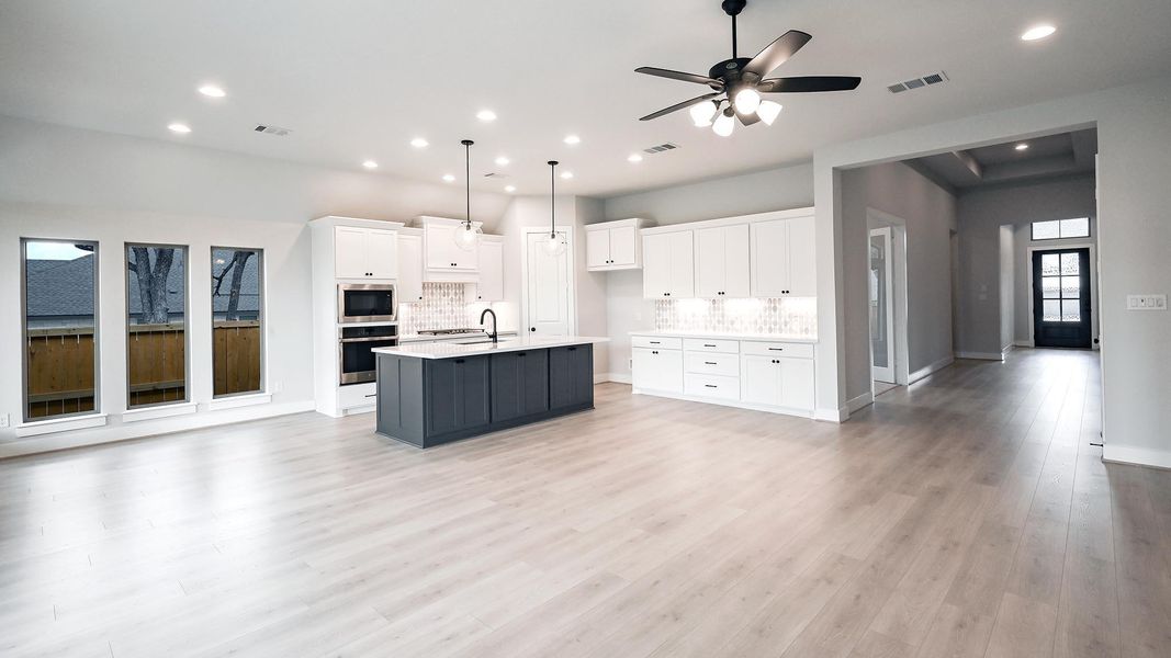 Kitchen with open floor plan, white cabinets, tasteful backsplash, a kitchen island with sink, and appliances with stainless steel finishes