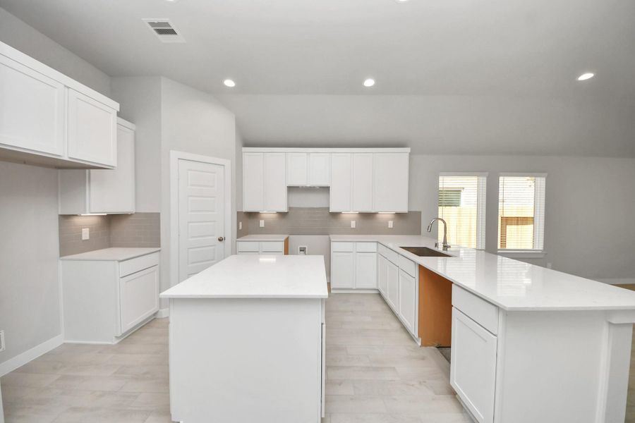 The kitchen is a culinary haven, featuring granite countertops, a tile backsplash, stainless steel appliances, 42” upper cabinets, and undercabinet lighting. Sample photo of completed home with similar floor plan. Actual colors and selections may vary.