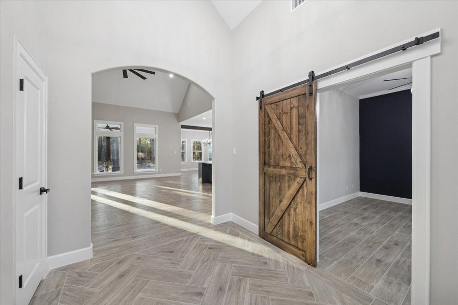 View from the front door.  Sliding barn door leads to office.  Door on the left is a coat closet.   Arched opening leads to the family room and kitchen.