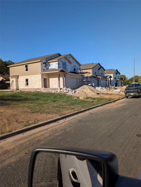 View of asphalt road featuring a residential view, curbs, and street lighting