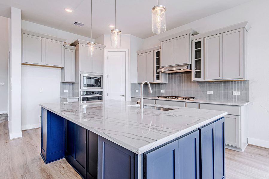 Crisp gray shaker cabinets, stainless steel appliances, and a stylish vertical tile backsplash elevate the kitchen’s design and functionality.