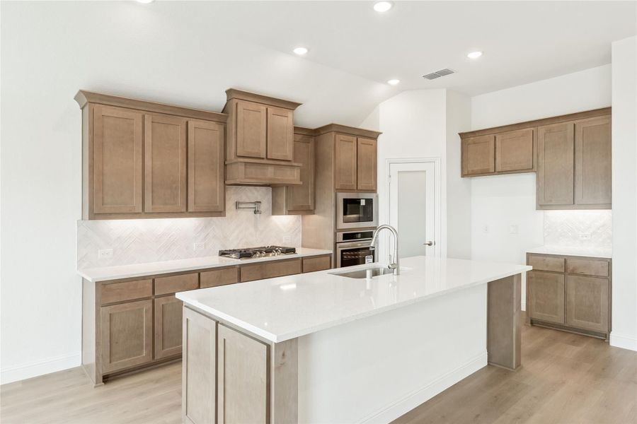 Kitchen with tan wood cabinets, white quartz countertops, large island with sink, and stainless steel appliances Kitchen with tan wood cabinets, white quartz countertops, large island with sink, and stainless steel appliances