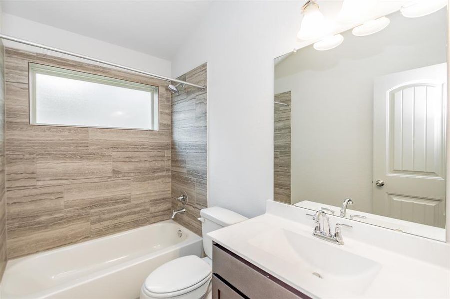 Relax and unwind in this beautifully designed bathroom featuring a soaking tub with stunning tile surround, modern fixtures, and a spacious vanity. The frosted window allows for natural light while maintaining privacy, creating the perfect balance of style and function. Ideal for rejuvenation after a long day.