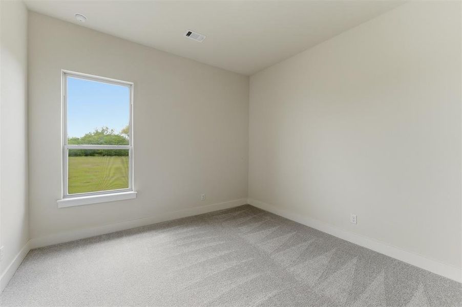 Bright room featuring neutral wall paint, light gray patterned carpet, and a large window with white trim