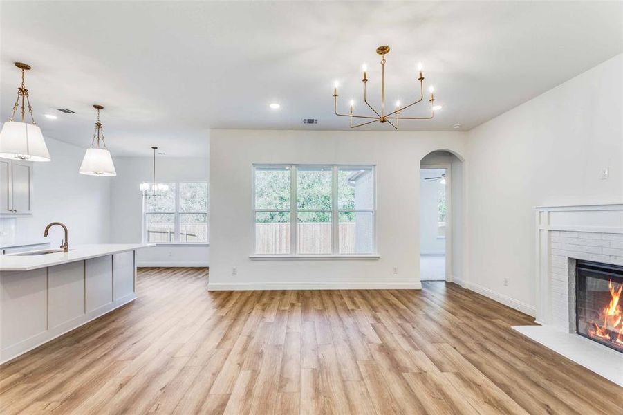 Unfurnished living room featuring sink, a fireplace, and light hardwood / wood-style flooring