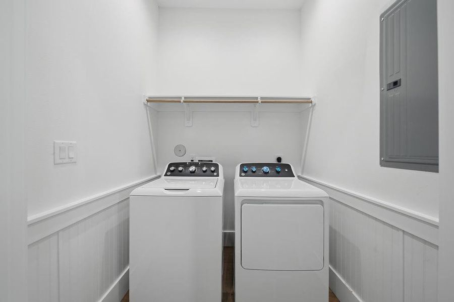 Compact laundry room with a washer and dryer, featuring a shelf above for storage. Bright and functional space with white walls and wood flooring.