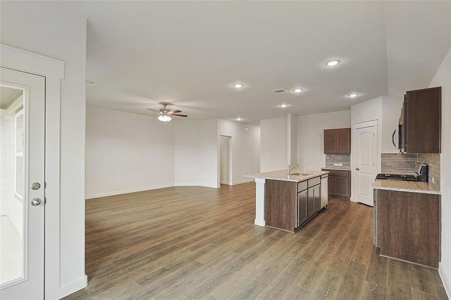 Kitchen featuring a center island with sink, sink, decorative backsplash, and dark hardwood / wood-style flooring