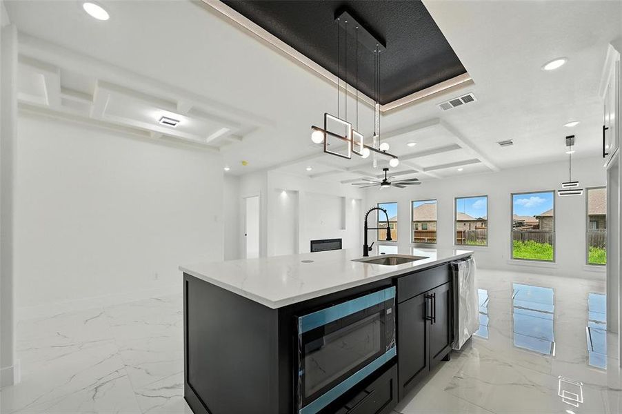 Kitchen with recessed lighting, light marble finish flooring, dark cabinetry, coffered ceiling, and open floor plan