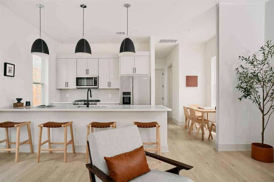 Modern kitchen featuring white cabinetry, light countertops, and stainless steel appliances