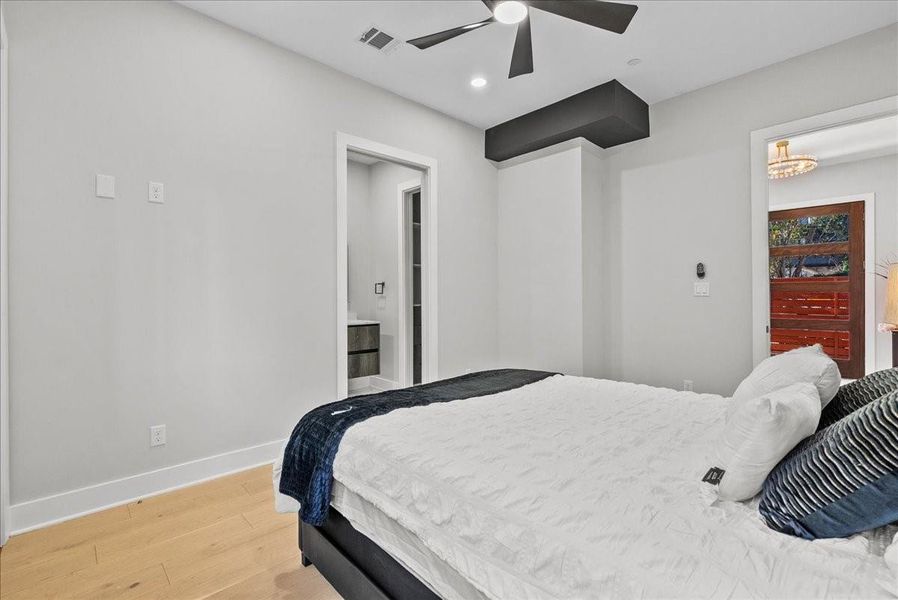 This bedroom features modern design with sleek finishes, light wood flooring, and a ceiling fan. It includes an en-suite bathroom and offers a minimalist aesthetic with neutral colors. This bedroom features modern design with sleek finishes, light wood flooring, and a ceiling fan. It includes an en-suite bathroom and offers a minimalist aesthetic with neutral colors.
