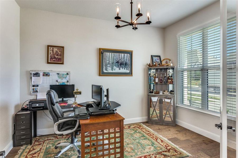 Office area with a chandelier and wood finished floors Office area with a chandelier and wood finished floors