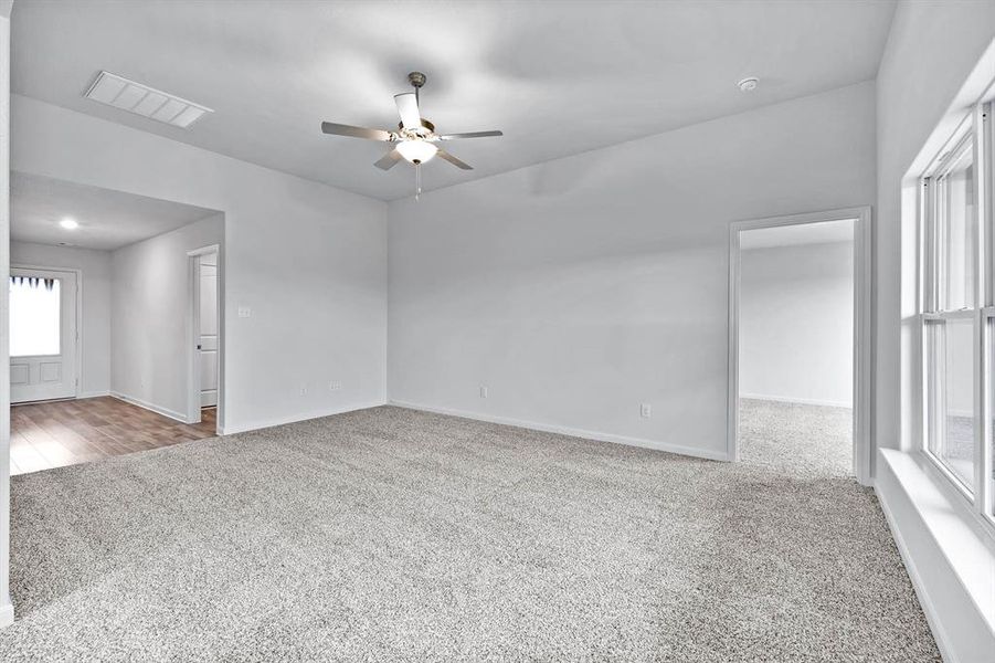 Empty room with light colored carpet and ceiling fan