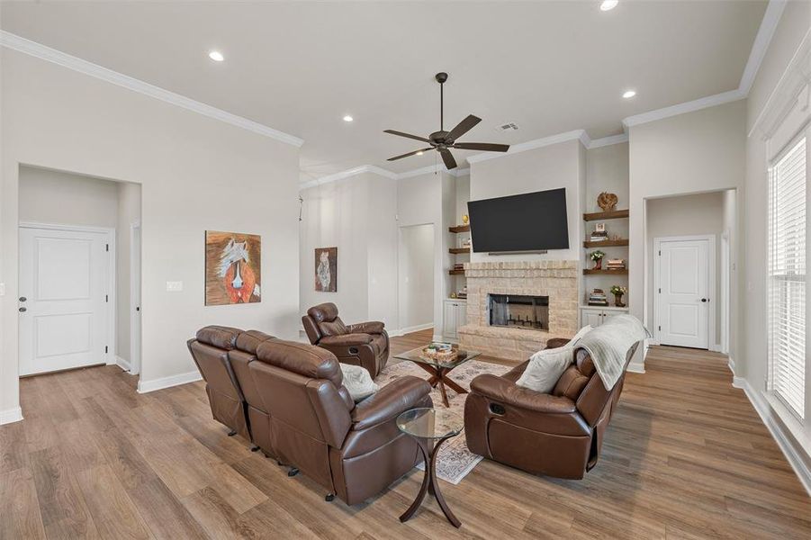 Living area with wood-burning fireplace, built-in shelving, and tall windows. Living area with wood-burning fireplace, built-in shelving, and tall windows.
