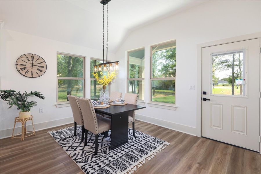 Dining area featuring plenty of natural light, lofted ceiling, and wood finished floors