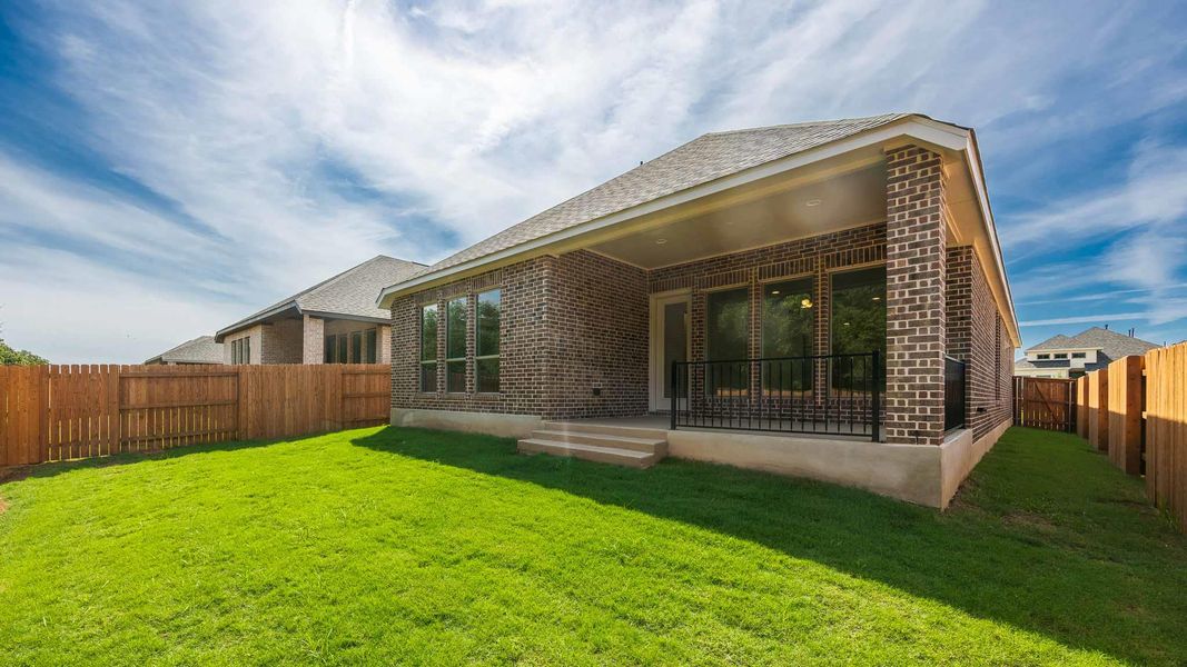 Back of house with a patio area, brick siding, a fenced backyard, and roof with shingles