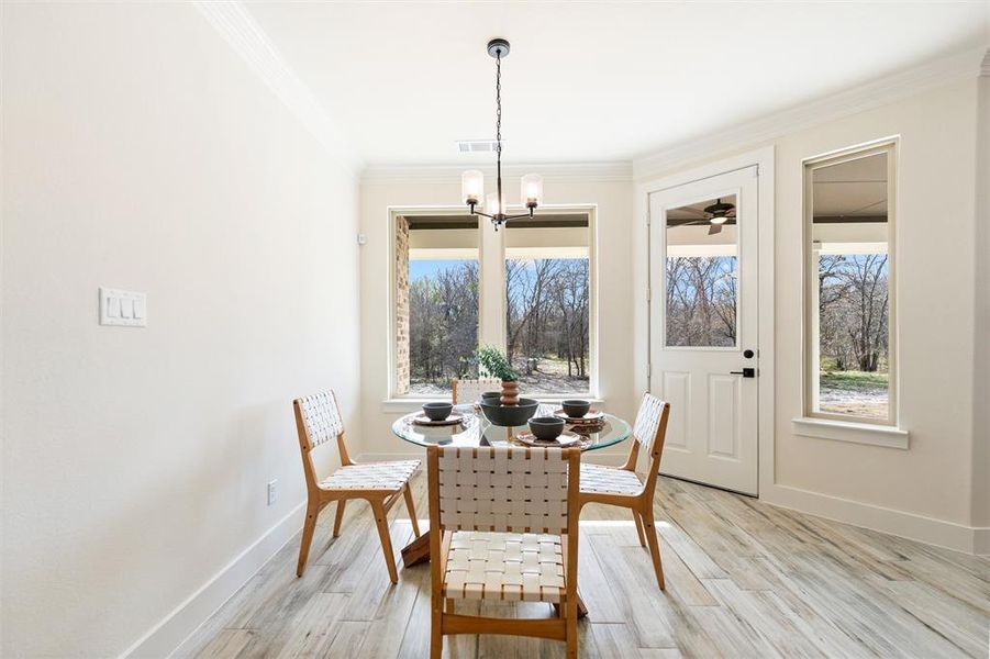 Dining room with light wood-style flooring, ornamental molding, and a chandelier
