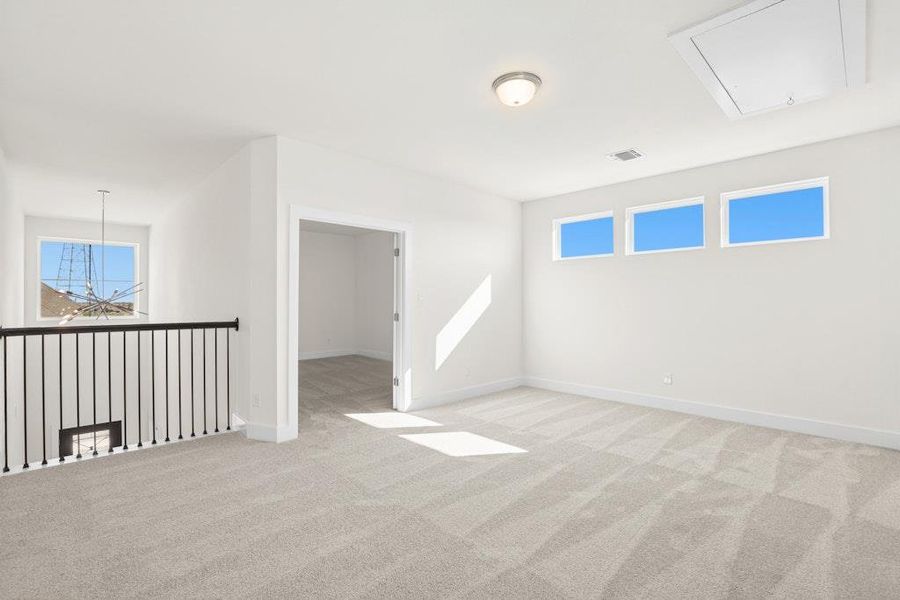 Empty room with attic access, light colored carpet, healthy amount of natural light, and a chandelier Empty room with attic access, light colored carpet, healthy amount of natural light, and a chandelier