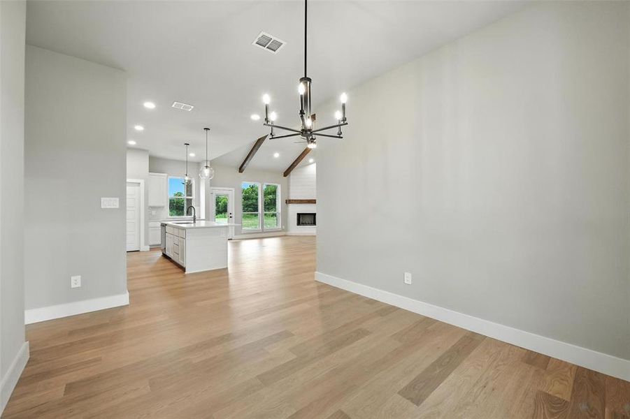 Unfurnished living room featuring recessed lighting, light wood finished floors, a chandelier, a fireplace, and vaulted ceiling Unfurnished living room featuring recessed lighting, light wood finished floors, a chandelier, a fireplace, and vaulted ceiling