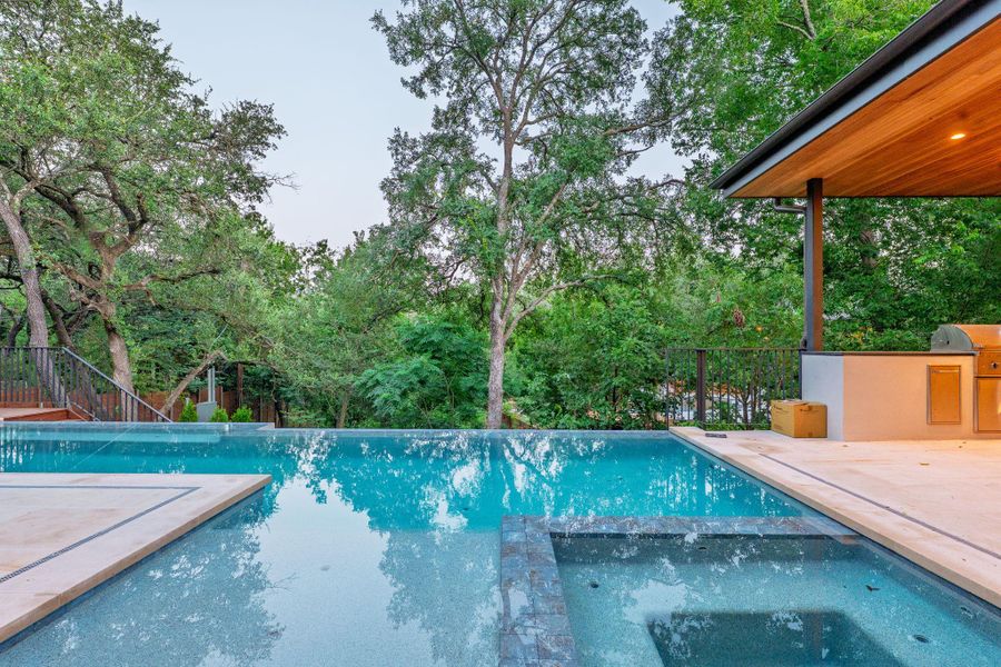 An inviting pool and spa area with a built-in outdoor kitchen, perfect for entertaining. An inviting pool and spa area with a built-in outdoor kitchen, perfect for entertaining.