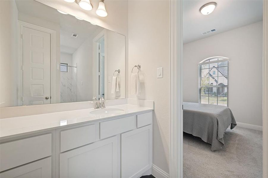 Private ensuite bath connected to the secondary bedroom, offering guests or multigenerational family members added comfort and privacy. Features a spacious vanity with quartz countertops, ample storage, and direct access to a beautifully appointed full bath with modern finishes Private ensuite bath connected to the secondary bedroom, offering guests or multigenerational family members added comfort and privacy. Features a spacious vanity with quartz countertops, ample storage, and direct access to a beautifully appointed full bath with modern finishes