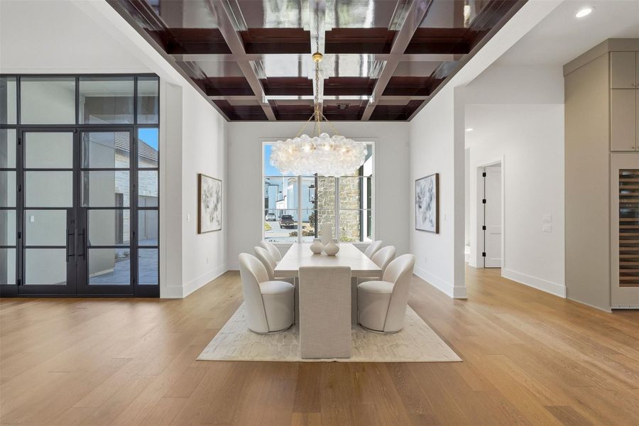 This elegant dining room features a modern, airy design that accommodates the most expansive table for your lavish dinner gatherings. A striking raisin-colored coffered ceiling, a statement chandelier, and ample natural light. The hallway you see to the right of this picture in the north wing of the home features a small room for a command center/bonus room/intimate reading lounge. Adjacent stairs lead to a private, seclude en-suite bed and bath (garage apartment) on the second floor. This elegant dining room features a modern, airy design that accommodates the most expansive table for your lavish dinner gatherings. A striking raisin-colored coffered ceiling, a statement chandelier, and ample natural light. The hallway you see to the right of this picture in the north wing of the home features a small room for a command center/bonus room/intimate reading lounge. Adjacent stairs lead to a private, seclude en-suite bed and bath (garage apartment) on the second floor.
