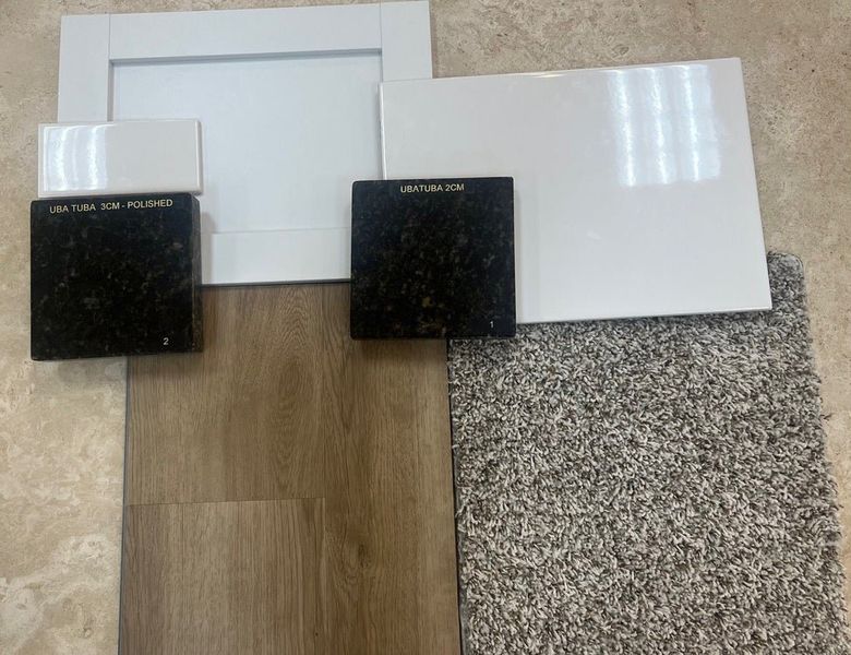 Home finish samples including Uba Tuba granite, white cabinet door, white tile, wood-look flooring, and gray carpet swatches