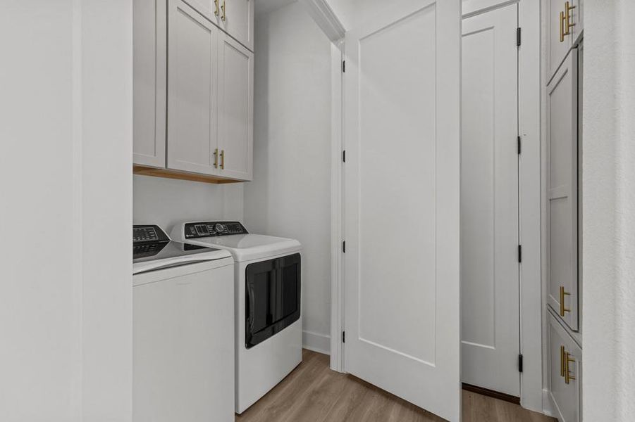Laundry area with cabinet space, light wood-style floors, and washer and clothes dryer