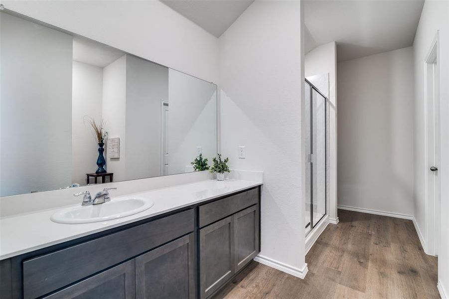 Full bath with a stall shower, wood finished floors, vanity, and baseboards