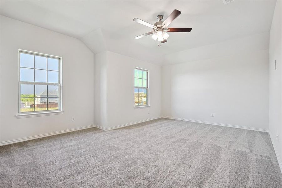 Spare room featuring ceiling fan, vaulted ceiling, and light colored carpet