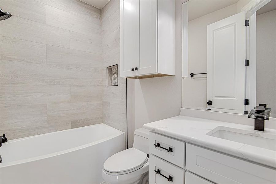 Full bath featuring shower / bathtub combination, vanity, and toilet Full bath featuring shower / bathtub combination, vanity, and toilet